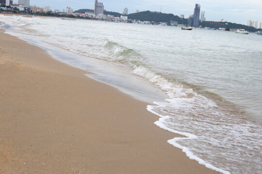 Close-up view of small ocean waves breaking on the sandy beach in Pattaya.
