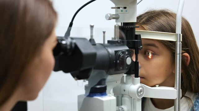 Young girl receives an eye exam from an optometrist using a phoropter in a well-equipped clinic, with various medical supplies in the background