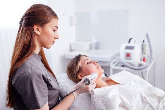 Female aesthetician performing facial treatment on a client in a modern spa environment, showcasing skincare techniques and professional equipment for beauty enhancement