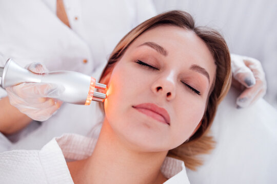 Female patient receiving facial treatment with advanced skincare device in a serene spa environment, showcasing modern beauty technology and relaxation techniques