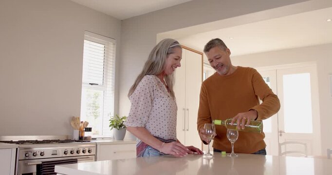 Senior couple enjoying wine together in modern kitchen, sharing joyful moment