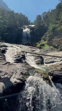 Waterfall Cascading Over Rocks in Forest River under Sunny Sky- vertical video