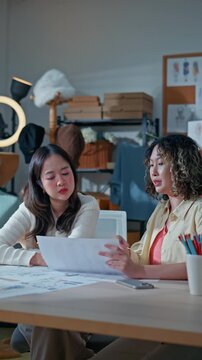 Two young female fashion designers and online clothing store owners meeting in home office, representing small business startup collaboration, e-commerce, creativity, business and technology