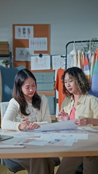 Two young female fashion designers and online clothing store owners meeting in home office, representing small business startup collaboration, e-commerce, creativity, business and technology
