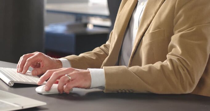Business professional typing on wireless keyboard and using mouse at office desk