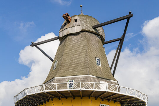 View of the historic windmill on the Hindsholm peninsula with its wooden shingled cap and white gallery railing against a blue sky in Kerteminde, Denmark.