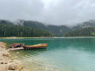 Naklejka premium Wooden boats on a misty forest lake in Durmitor Montenegro
