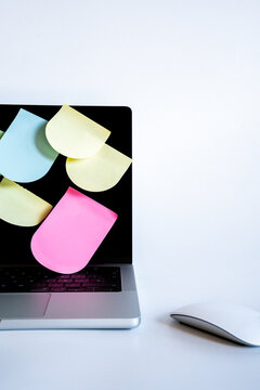 Laptop screen with colorful sticky notes, showing reminders, busy schedule, productivity, and organization on a desk