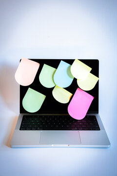 Laptop screen overflowing with colorful sticky notes, visualizing too much information, multitasking, and digital overload