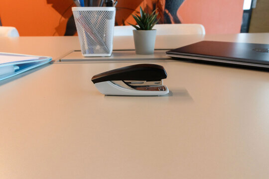Black and white stapler on a light desk surface in close-up. It represents minimalist office equipment and everyday stationery.