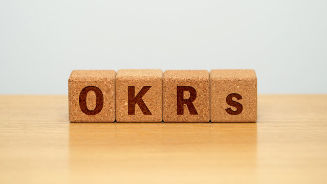 OKRs on four cork wooden blocks - objectives and key results concept