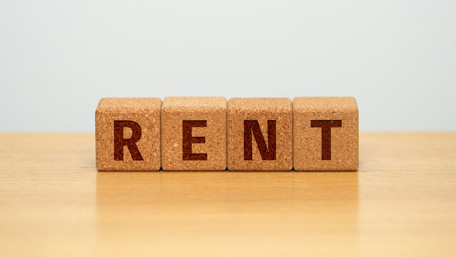 RENT on four cork wooden blocks - rent and housing costs concept