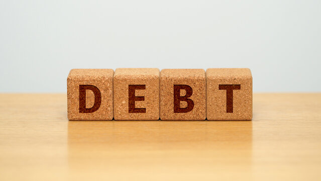 DEBT on four cork wooden blocks - debt and borrowing concept