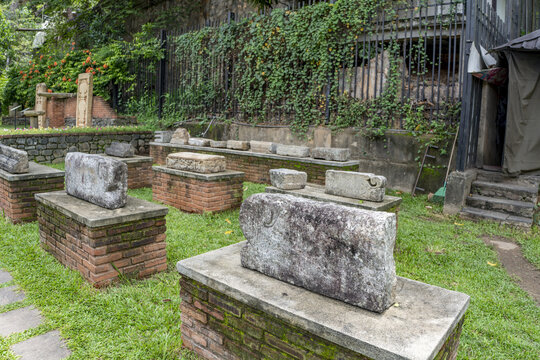 View of ancient stone artifacts displayed on brick pedestals within the historic grounds of the Sri Dalada Maligawa in Kandy, Central Province, Sri Lanka.