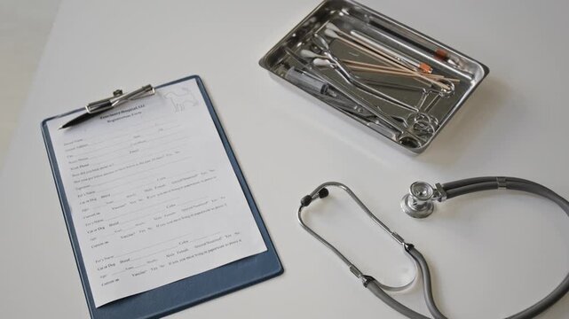 Veterinary registration form, stethoscope, and medical tool tray lying on table in top view. Footage suitable for animal clinic promos and pet healthcare advertising