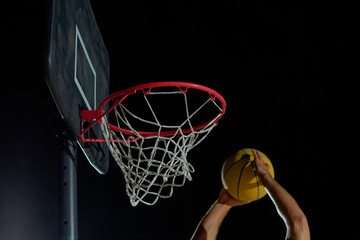 A man performs a slam dunk on a basketball court at night under the glare of bright outdoor lights © nazariykarkhut