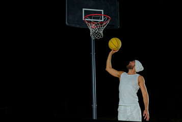 A man performs a slam dunk on a basketball court at night under the glare of bright outdoor lights © nazariykarkhut