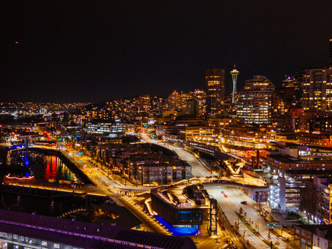 Seattle downtown skyline and waterfront with illuminated ferris wheel reflecting on Elliott Bay at night aerial view. g.