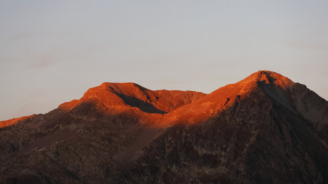 View of the Bel Oiseau mountain peak illuminated by the warm light of the golden hour with rugged rocky slopes in Finhaut, Valais, Switzerland.