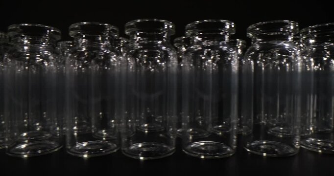 Neat rows of empty medical glass vials stand on clean surface. Pharmaceutical vials designed for injectable medicines and vaccines in laboratory