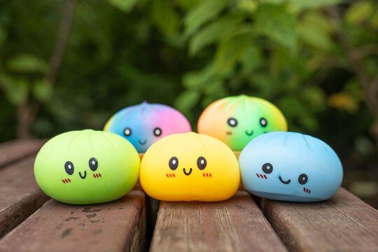 Close up of colorful smiling squishy toys on wooden bench outdoors with copy space