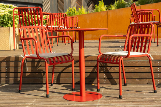Red metal chairs and table on outdoor cafe terrace in bright daylight