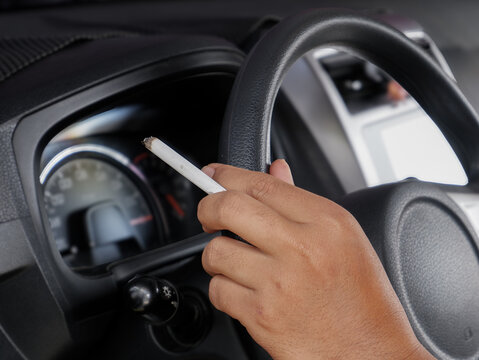 Driver Hand Holding Lit Cigarette While Driving Inside Car Interior Close Up