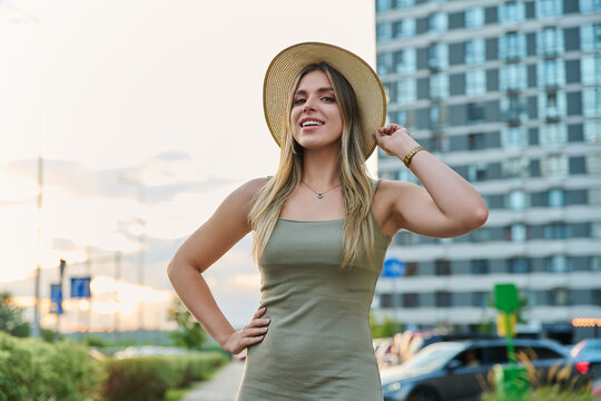 Smiling young woman in straw hat looking at camera outdoors