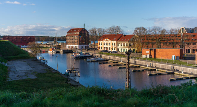 View of the historic harbor and marina in Klaipeda with traditional brick buildings, moored boats, and calm water under a clear blue sky in Klaipeda, Klaipeda County, Lithuania.