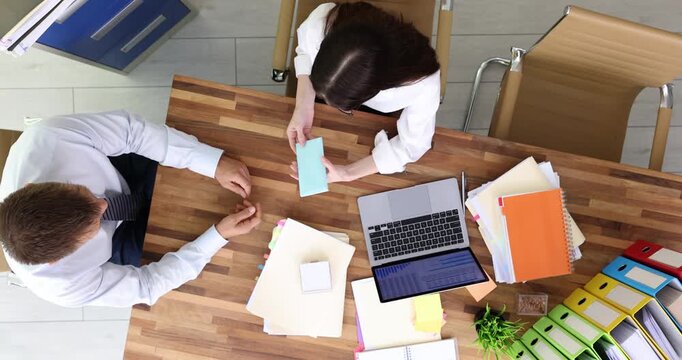 Man offers thick envelope filled with cash to executive. Businesswoman means envelope with money as attempt to obtain unfair advantage and refuses