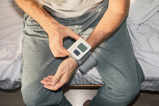 Man measuring his blood pressure using digital wrist device while sitting