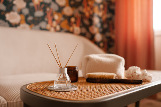 Home cozy atmosphere with liquid diffuser in glass bottle on rattan table close up in living room close up. Aromatherapy.