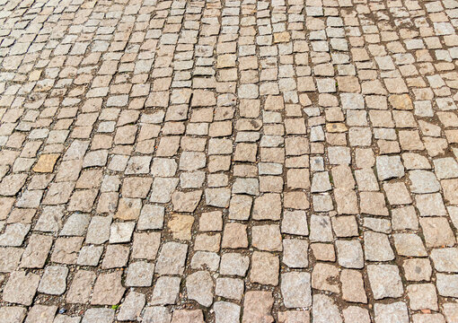 High angle perspective view of an old cobblestone street paved with natural stone blocks. Texture
