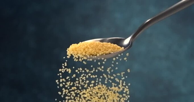 Couscous falling from a spoon in slow motion close up on blue background