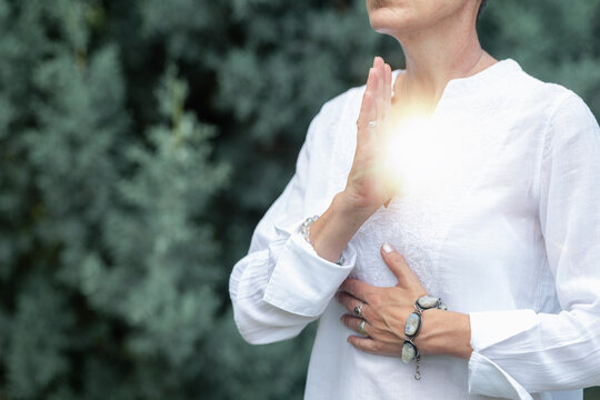 Mindfulness practice with hands over the heart chakra and healing light, spiritual wellness