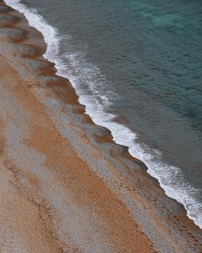 View of the pebble beach with gentle waves washing onto the shore in Cornwall, England, United Kingdom.