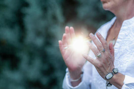 Mindfulness practice holding a glowing light orb between the hands, spiritual energy healing,
