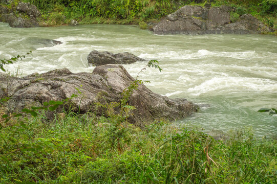 Rushing muddy rapids around large boulders, the Tama River swollen after heavy rain in Mitake Gorge, Ome, Tokyo