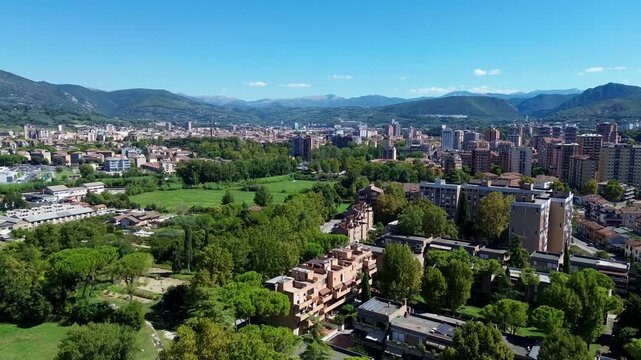 High-angle drone video showing Terni, Italy, with terracotta rooftops, green hills and trees blending into the surrounding Umbrian countryside and rolling landscape.