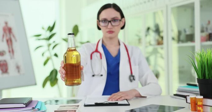 Female doctor holds alcohol bottle at health consultation. Physician presents drink discussing possible harm effects on patient wellbeing slow motion