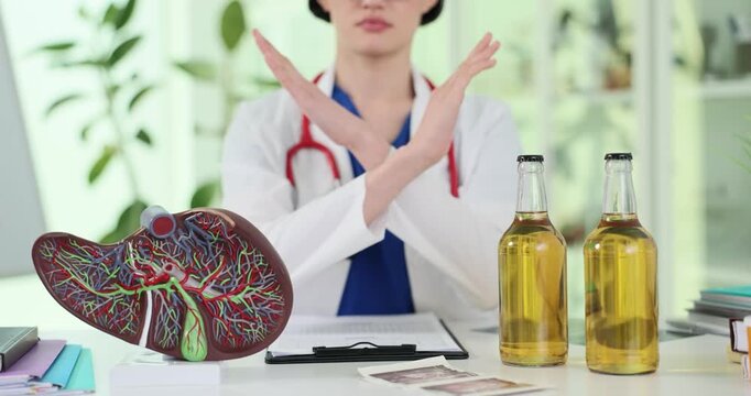 Female doctor warns against alcohol intake by anatomical liver model. Physician crosses arms signaling refusal as discussing liver health slow motion