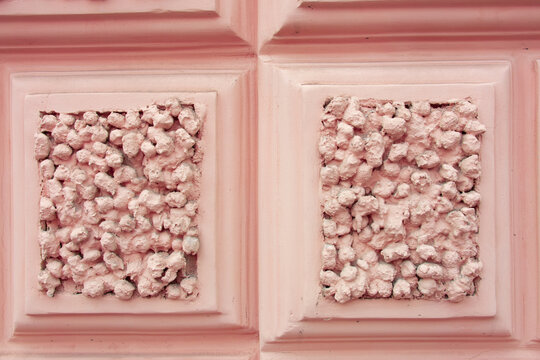 Pink building facade with rusticated decorative wall panels