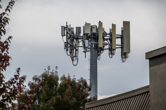 View of a telecommunications cell tower with multiple antennas and cabling against a cloudy sky in Portland, Oregon, United States.
