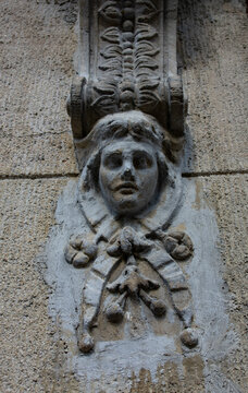 Weathered stone mascaron carved as a face on a facade corbel