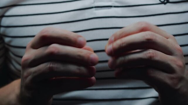 The man is nervous and is fidgeting with his fingers.
The man is picking at his fingers.