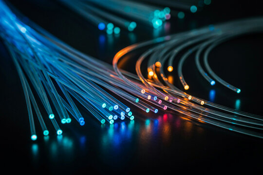 Multiple bundles of colorful glowing fiber optic cables illuminated in blue and orange on a dark surface with optical fiber optics cable bundles data cable