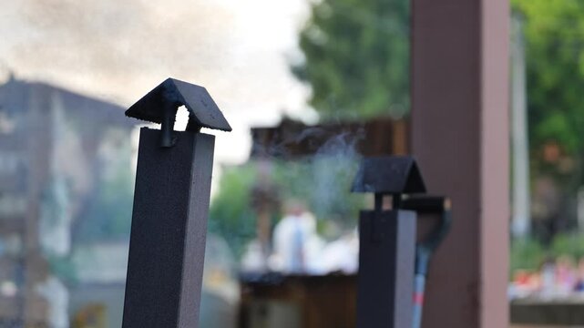 Grill chimneys emitting smoke during a outdoor barbecue, preparing food for a gathering