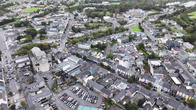Wide aerial drone footage overlooking Westport, County Mayo, Ireland, revealing the historic town centre, residential neighborhoods, colorful buildings, church architecture, roads, car parks, sports