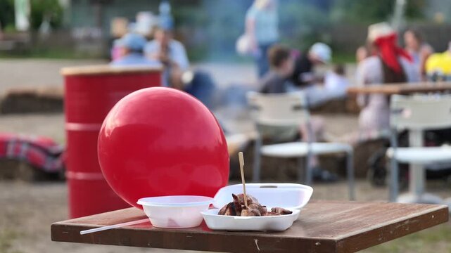 Barbecue food and red balloon on table at outdoor festival gathering