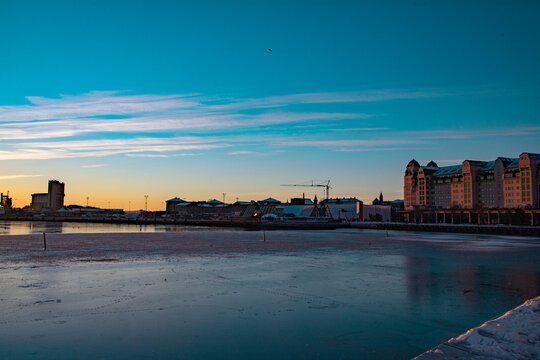 View of the frozen Oslofjord waterfront at sunset with the modern architecture of the Barcode Project buildings, icy water, and a clear winter sky in Oslo, Oslo, Norway.